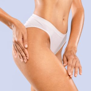 Love Yourself, Skincare Concept. Half-turned Tender Slim Lady With Perfect Ideal Body Shape Touching Soft Skin On Her Hips With Hands Posing Isolated On Blue Studio Background, Massaging Thigh