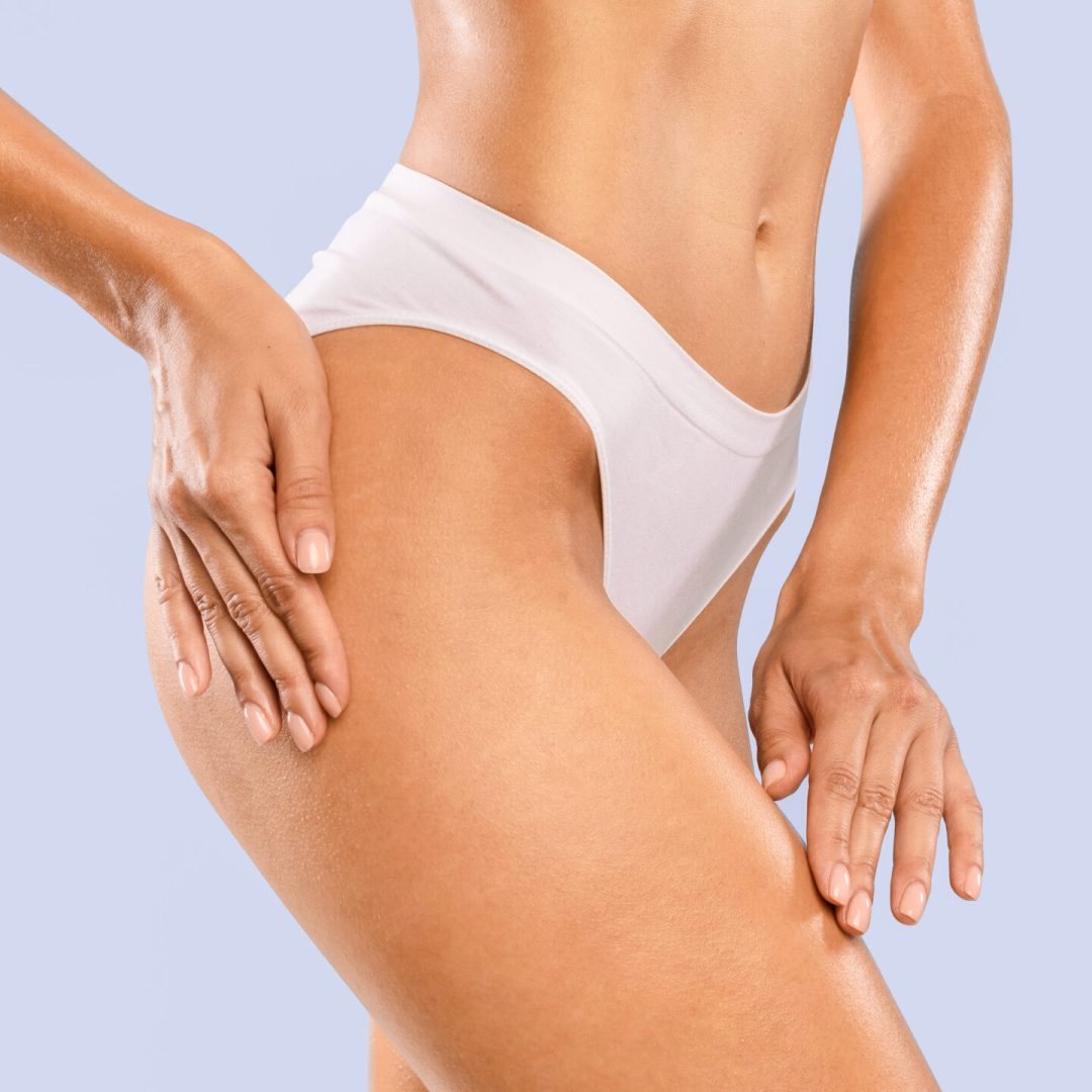 Love Yourself, Skincare Concept. Half-turned Tender Slim Lady With Perfect Ideal Body Shape Touching Soft Skin On Her Hips With Hands Posing Isolated On Blue Studio Background, Massaging Thigh